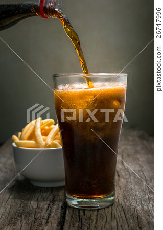 Pouring cola into the glass on wooden table Pouring cola into the glass on wooden table 26747996