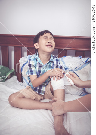 Child injured. Mother bandaging son's knee. 26762545