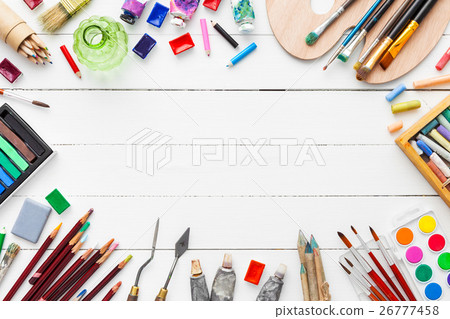 Paints, brushes, pencils, pastel crayon on desk. 26777458