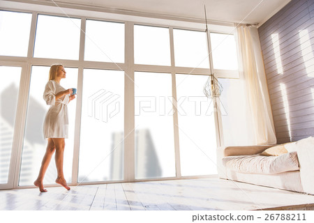 Dreamful girl enjoying hot beverage in living room Dreamful girl enjoying hot beverage in living room 26788211