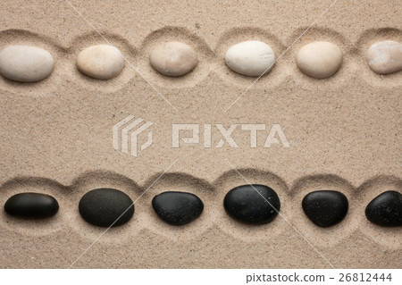 White and black stones lying  in  the sand 26812444