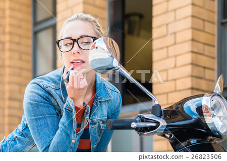 Girl uses rearview mirror of scooter Girl uses rearview mirror of scooter 26823506