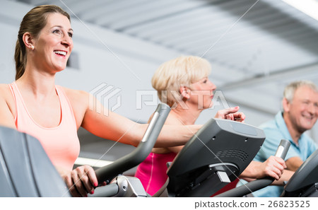 Young woman and senior couple spinning at the gym 26823525