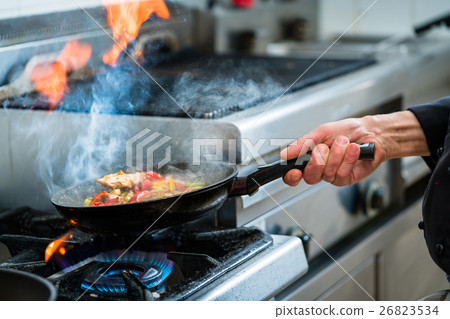 Chef doing flambe to food in pan with alcohol Chef doing flambe to food in pan with alcohol 26823534