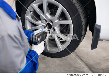 car mechanic screwing or unscrewing wheel of car mechanic screwing or unscrewing wheel of 26830557