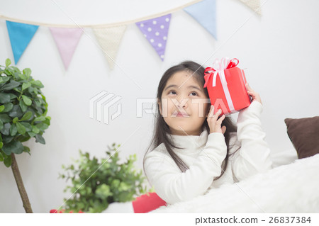 Happy Asian girl shaking a present to guess whats 26837384