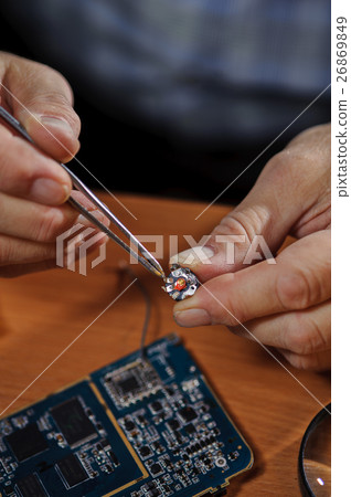 Electronic engineer holding chip with tweezers 26869849