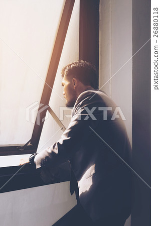 Businessman is thinking in front of a window Businessman is thinking in front of a window 26880118