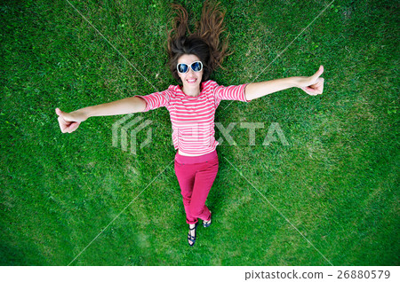 beautiful young woman lying on the green grass in 26880579