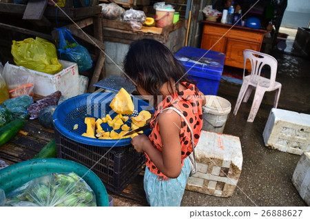 泰國城市和柬埔寨邊境Alanyaprathet市場泰國方面幫助切菜的女孩 泰國城市和柬埔寨邊境Alanyaprathet市場泰國方面幫助切菜的女孩 26888627