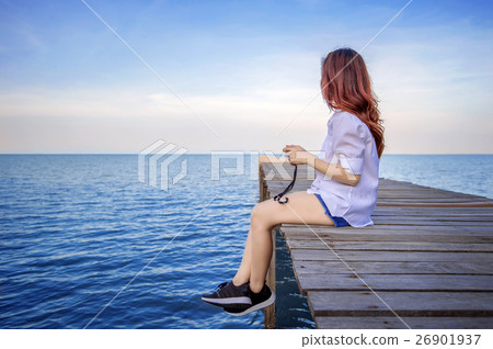 Girl sitting alone on a the wooden bridge. 26901937