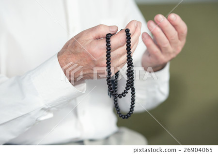 Praying hands of an old man holding rosary beads 26904065