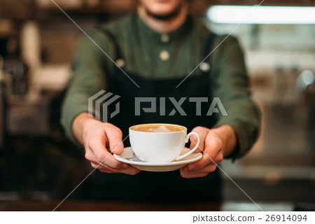 Waiter in black apron stretches a cup of coffee Waiter in black apron stretches a cup of coffee 26914094