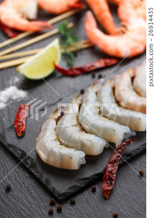 Raw and boiled shrimps on a stone plate 26914435
