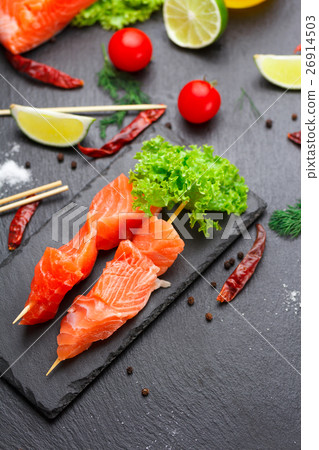 Raw salmon skewers on a stone plate. 26914503