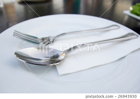 spoon and fork with white plate on table 26943930
