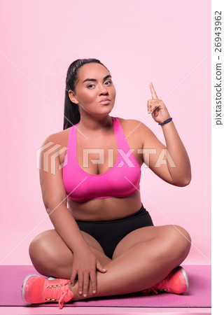 Woman sitting on floor and pointing up with index 26943962
