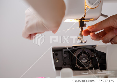 Girl inserts thread in sewing-machine Girl inserts thread in sewing-machine 26948479