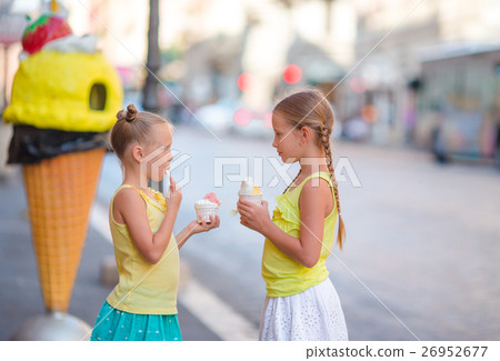 Happy little girls eating ice-creamin open-air Happy little girls eating ice-creamin open-air 26952677