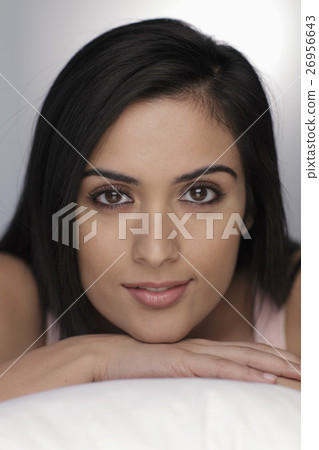 Head shot of young woman resting her chin on hands and smiling 26956643