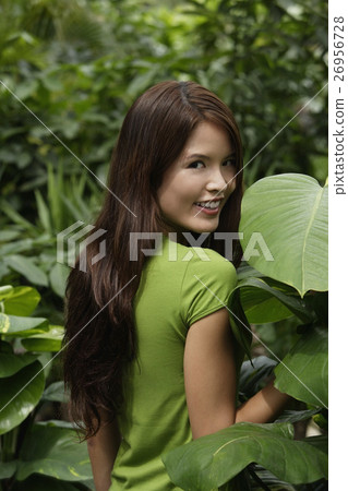 Young woman standing among plants 26956728