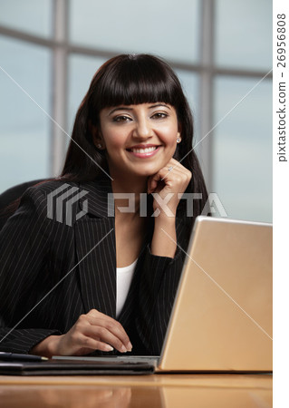 Indian woman smiling while working on laptop Indian woman smiling while working on laptop 26956808