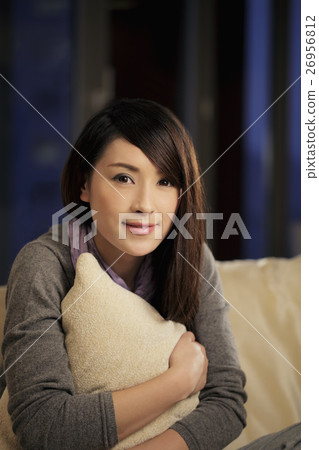 Young woman holding a pillow and smiling 26956812