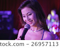 Young woman singing into a microphone at night 26957113