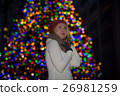 Beautiful young woman with christmas tree in the background 26981259