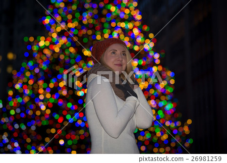 Beautiful young woman with christmas tree in the background 26981259