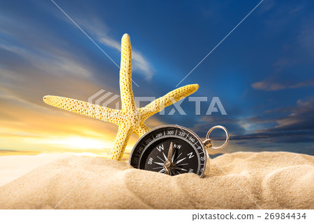Sea star and compass in sand on sunset Sea star and compass in sand on sunset 26984434