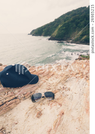 Sunglasses and cap on the top of mountain 26985215