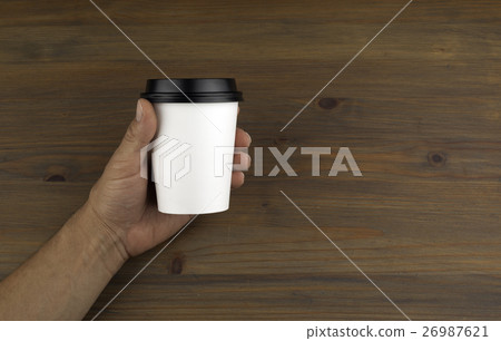 Paper cup of coffee in hand on wooden background 26987621