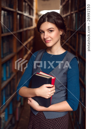 Student girl with books between bookshelves Student girl with books between bookshelves 26991550