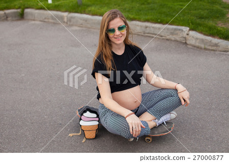 Pregnant woman sitting on the skateboard  27000877