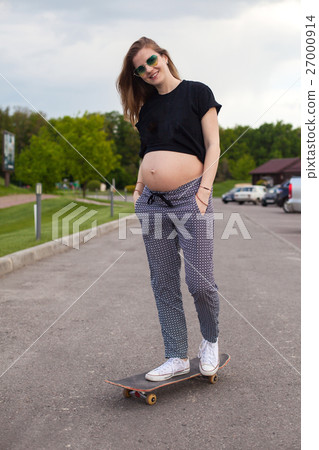 Pregnant woman skateboarding on the road  27000914
