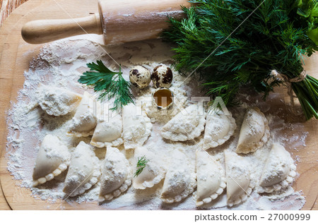 Raw dumplings, flour, eggs on a wooden board. 27000999