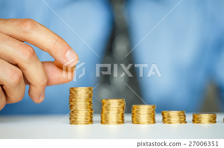 Male hand stacking gold coins into columns Male hand stacking gold coins into columns 27006351