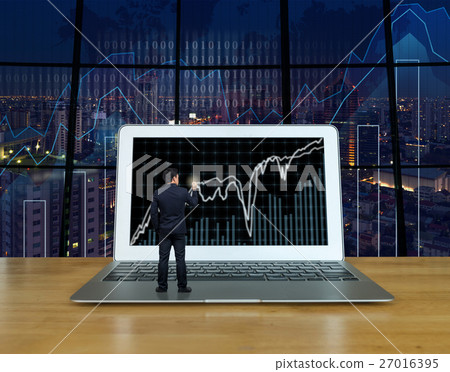 Businessman standing over the computer laptop on the wood table and writing the trading graph at the screen over the blurred photo of trading graph on cityscape background, Business trading concept 27016395