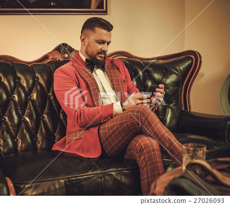 Extravagant stylish man sitting on classic leather Extravagant stylish man sitting on classic leather 27026093