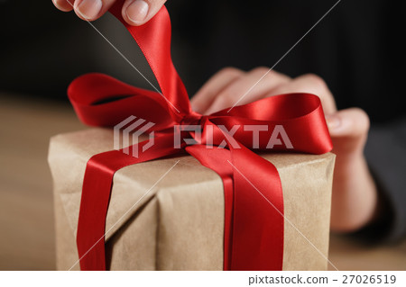 female teen hand going to untie bow on gift box 27026519