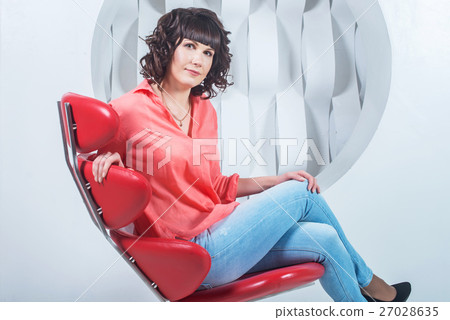 Woman sitting in red chair against white wall Woman sitting in red chair against white wall 27028635