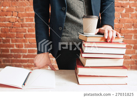 Student near stack of books and coffee-to-go cup Student near stack of books and coffee-to-go cup 27031825