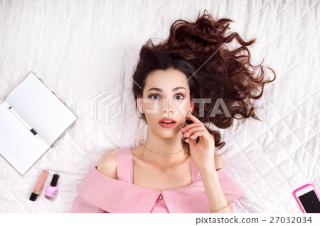 Serious woman lying on bed top view 27032034