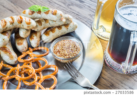 Grilled sausages with pretzels and mugs of beer 27033586