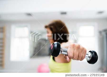 Senior woman in gym working out with weights. 27035149