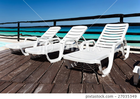 Luxury sunbeds on wooden floor near swimming pool Luxury sunbeds on wooden floor near swimming pool 27035349