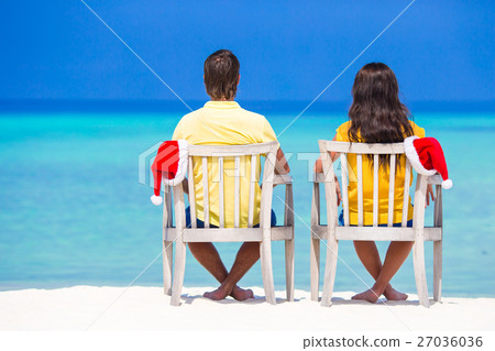 Young couple in Santa hats relaxing on tropical Young couple in Santa hats relaxing on tropical 27036036