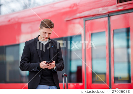 Young caucasian man with smarphone and luggage at Young caucasian man with smarphone and luggage at 27036088
