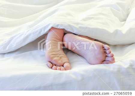Feet of sleeping woman in white bed room Feet of sleeping woman in white bed room 27065059